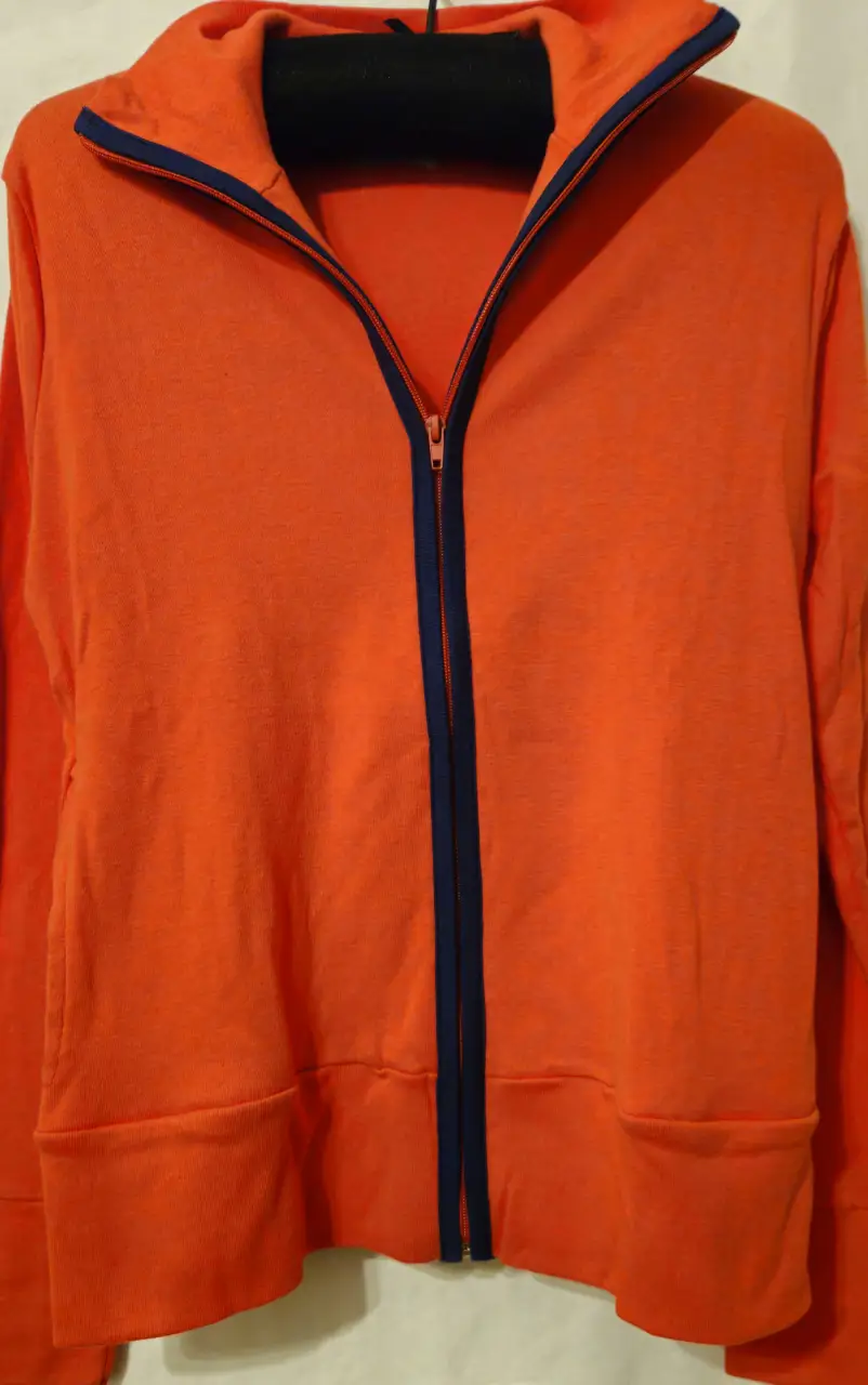 Buzo naranja con cierre y detalles en azul. Ideal para un look deportivo y cómodo. Perfecto para el día a día.