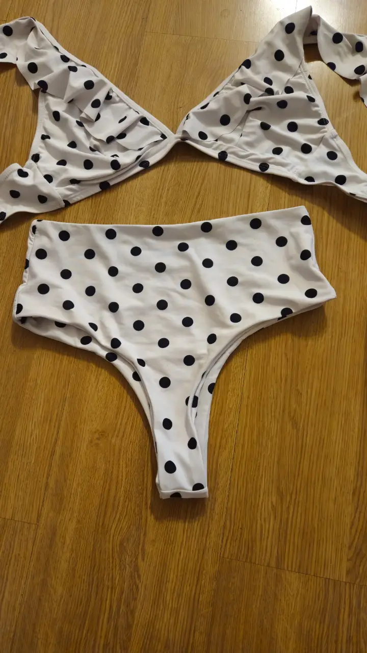 Conjunto de bikini con estampado de lunares blancos y negros. Incluye top triangular con volados y bombacha tiro alto.