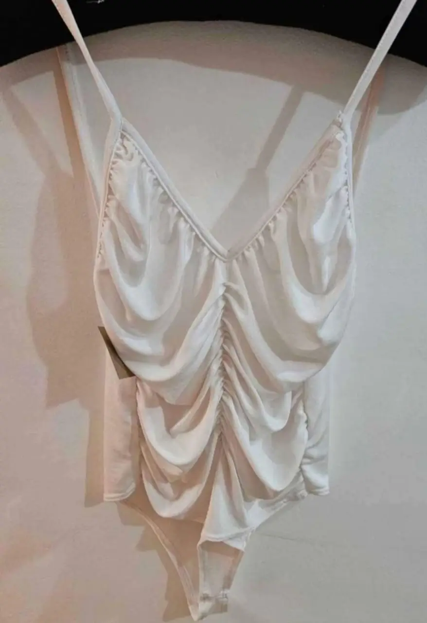 Body blanco con fruncidos en la parte delantera y tirantes finos. Ideal para un look elegante y moderno.