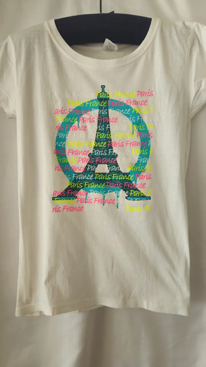 Remera blanca con estampado de la Torre Eiffel y la frase "Paris France" en varios colores. Ideal para un look casual y con onda.