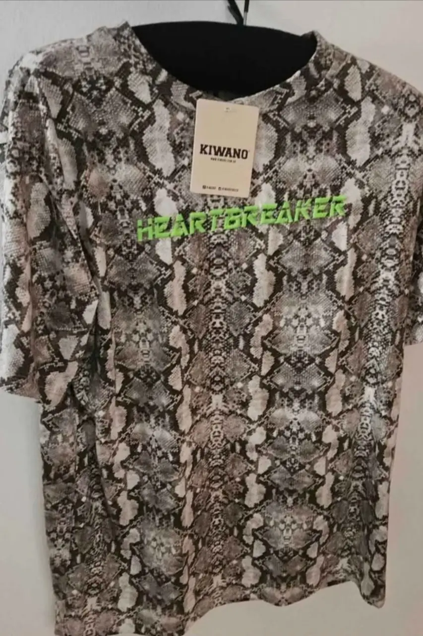 Remera de hombre con estampado de piel de serpiente y la palabra "HEARTBREAKER" en verde flúo. Ideal para un look urbano y audaz.