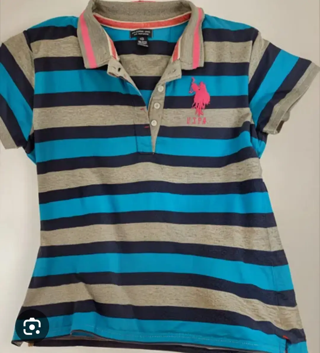 Remera polo de mujer a rayas horizontales en azul, gris y celeste. Con el logo de la marca USPA en rosa. Ideal para un look casual y deportivo.