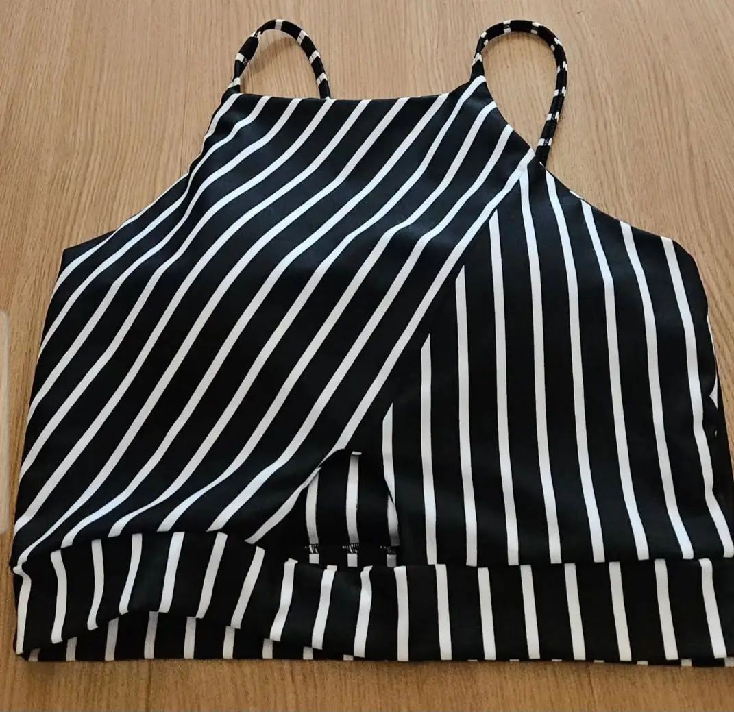 Top armado a rayas blanco y negro. Diseño con tirantes finos y corte asimétrico. Ideal para  looks casuales.