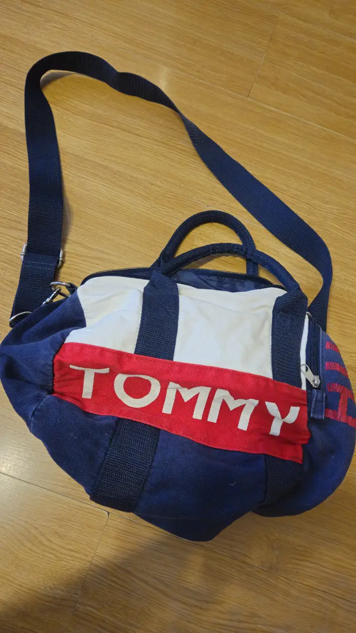 Bolso deportivo Tommy Hilfiger, ideal para llevar al gimnasio o para viajes cortos. Confeccionado en lona resistente, presenta los colores icónicos de la marca y un diseño clásico. Cuenta con manijas, y correa ajustable para llevar al hombro. Medida 40*30 cm .