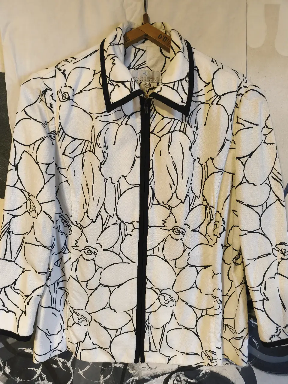 Blazer de mujer con estampado floral en blanco y negro. Corte clásico con solapas y cierre frontal con cremallera. Ideal para un look elegante y moderno.