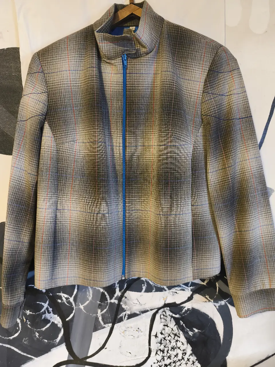 Chaqueta campera a cuadros en tonos marrones, beige y blanco, con cierre y forro interior azul. Ideal para un look elegante y sofisticado.