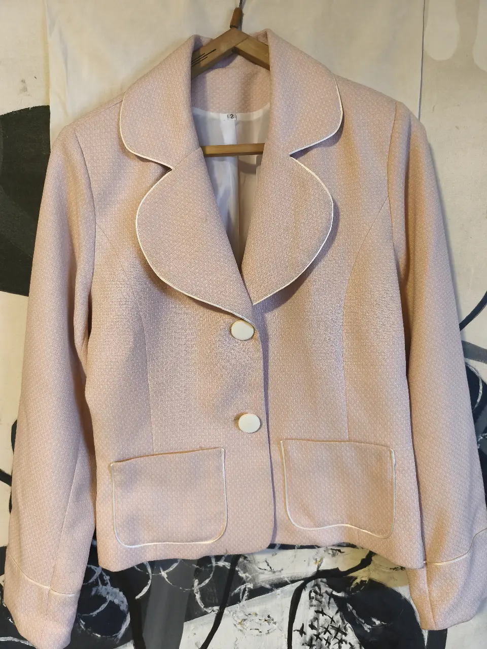 Elegante blazer rosa con detalles en blanco. Ideal para un look formal o de trabajo. Corte clásico con dos botones y bolsillos delanteros.
