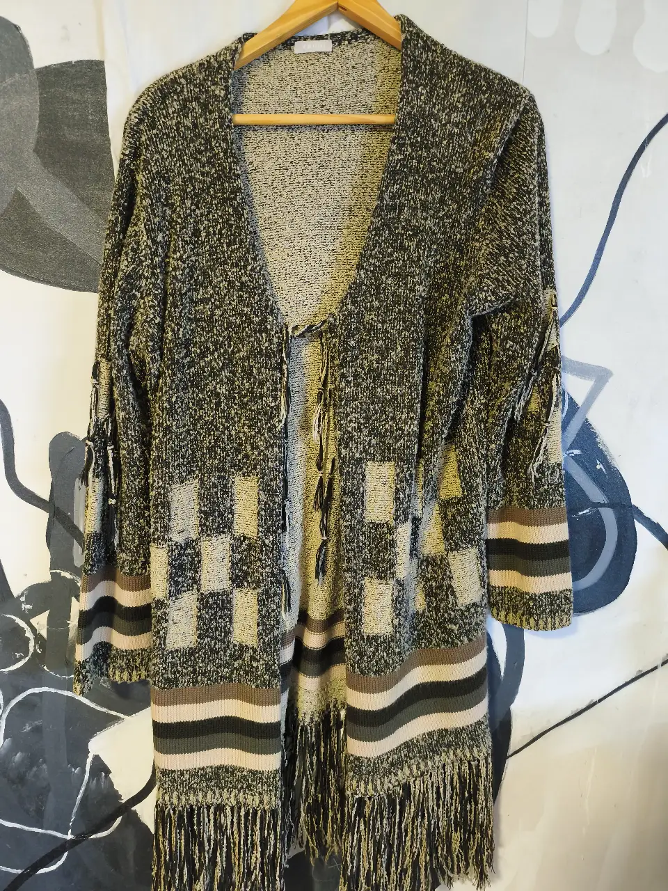 Cardigan largo de tejido grueso con diseño a cuadros y flecos en el bajo. Ideal para un look casual y abrigado.