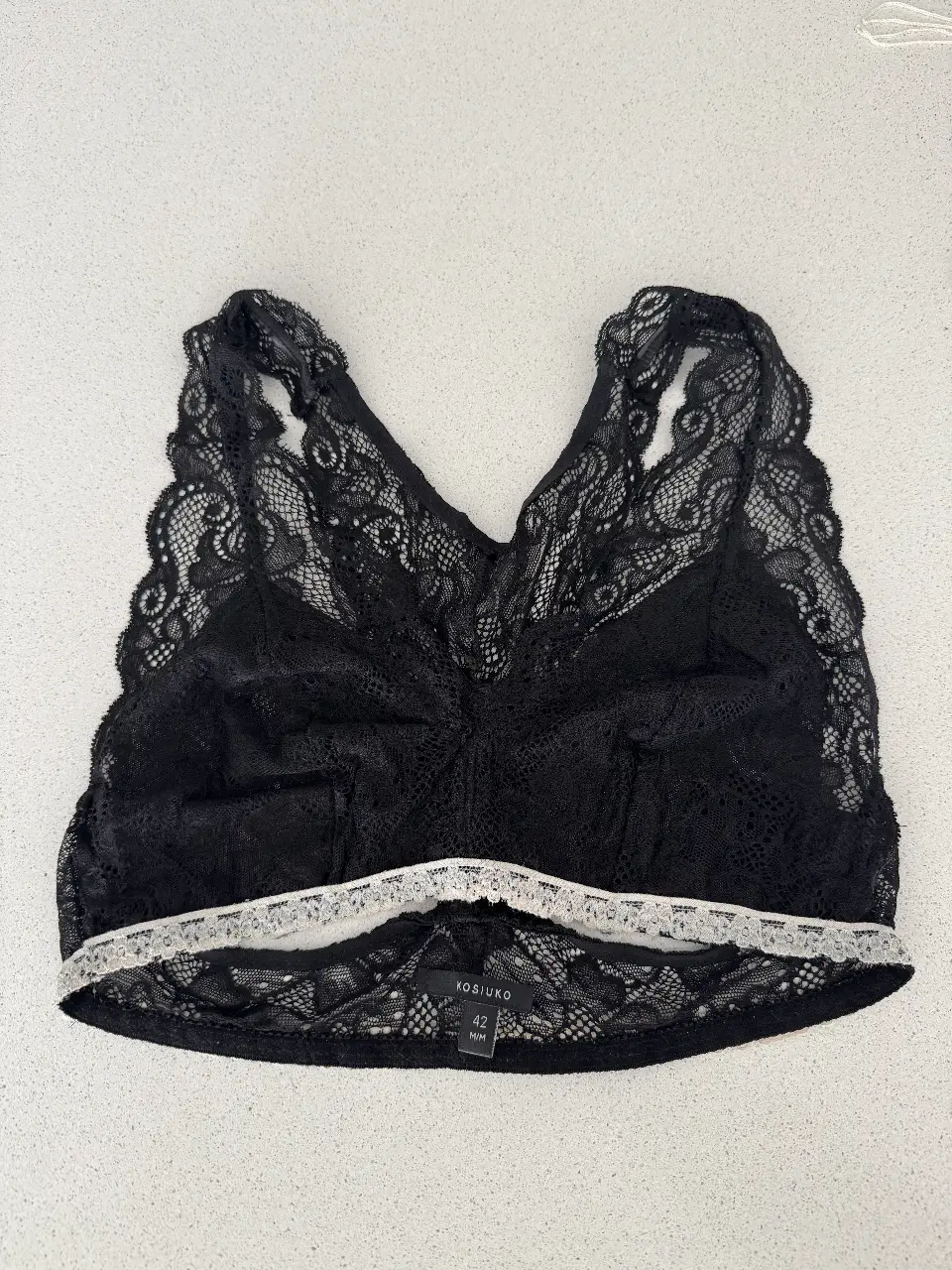 Corpiño de encaje negro, estilo bralette, con detalles de encaje blanco en el borde inferior. Talle 42.