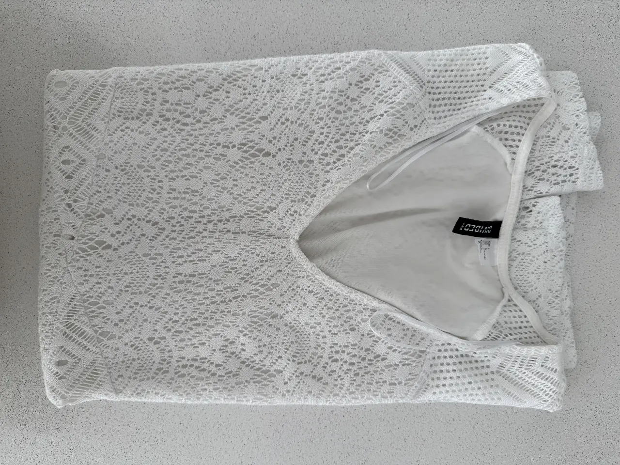 Vestido mini blanco de encaje, ideal para un look fresco y veraniego. Perfecto para usar en la playa o en una salida casual.
