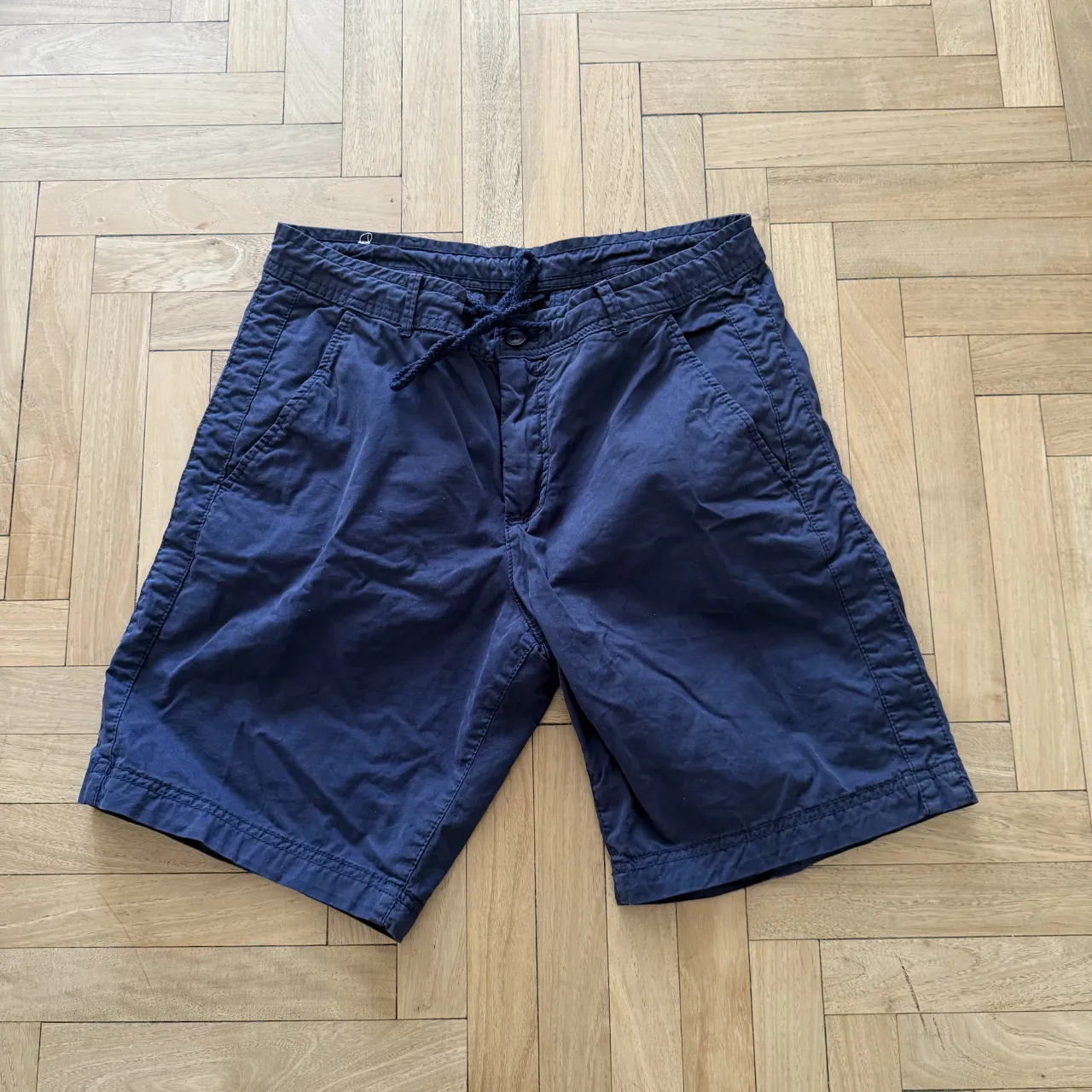 Bermuda de gabardina azul marino con cordón ajustable en la cintura y bolsillos delanteros.