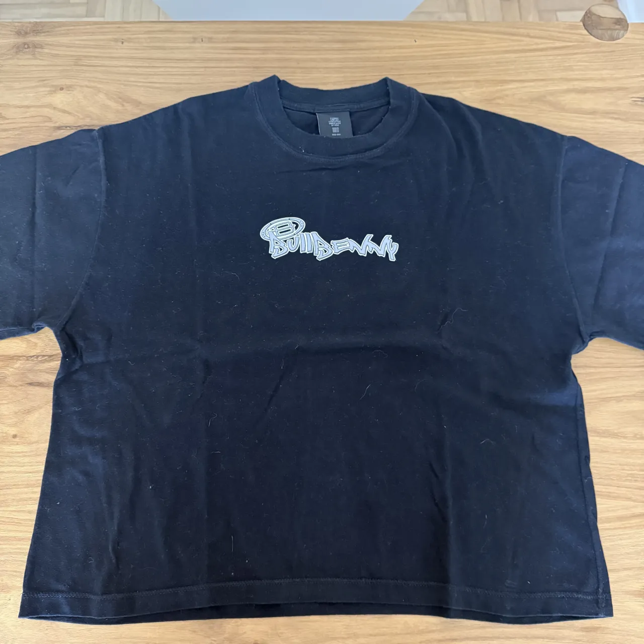 Remera BULLBENNY negra con estampa blanca en el frente y un logo ovalado blanco en la espalda.