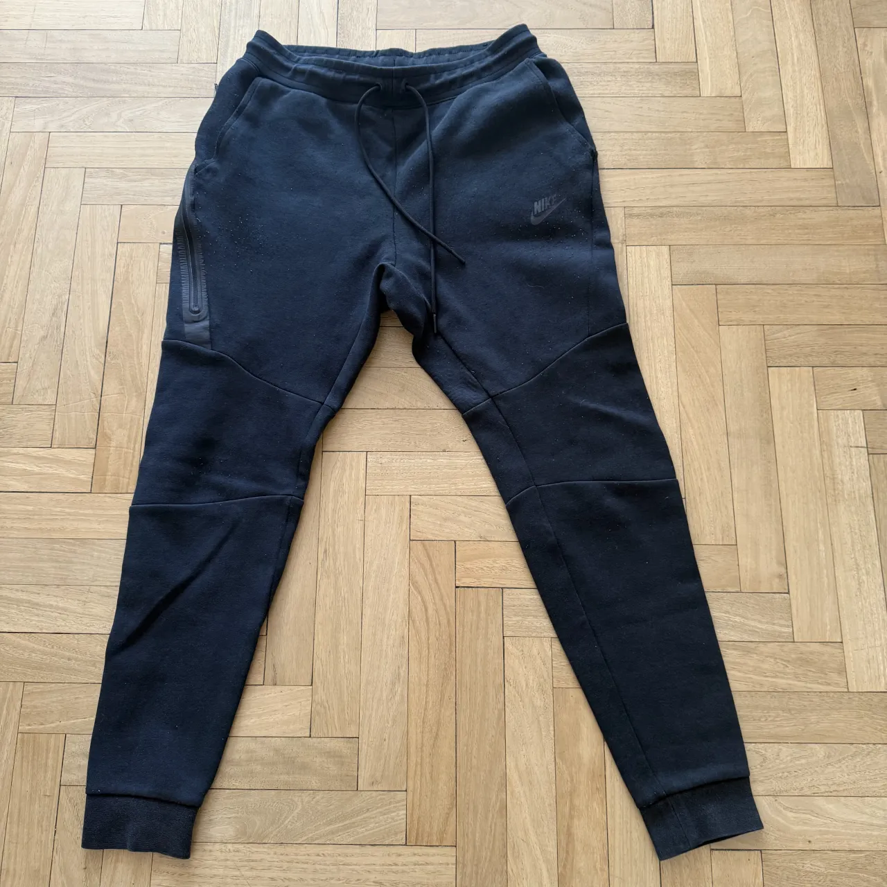 Pantalón NIKE de jogging negro con cordón en la cintura y logo de la marca en la pierna izquierda.