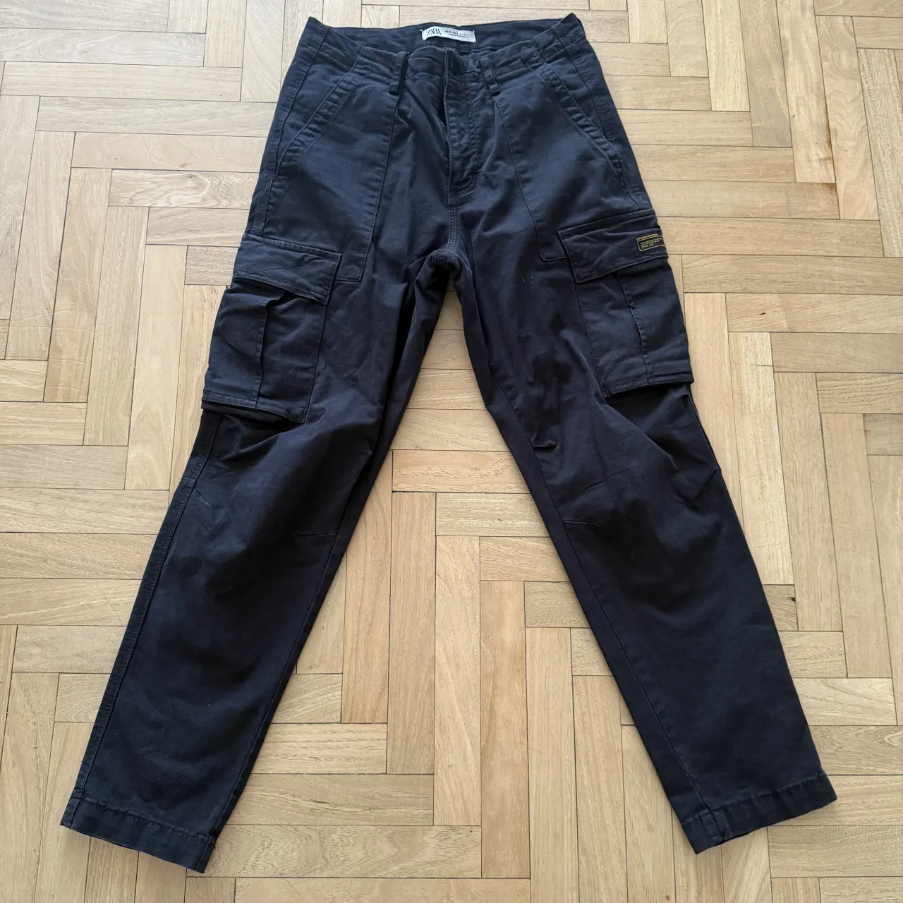 Pantalon ZARA cargo negros con bolsillos laterales y etiqueta de marca en el bolsillo derecho.