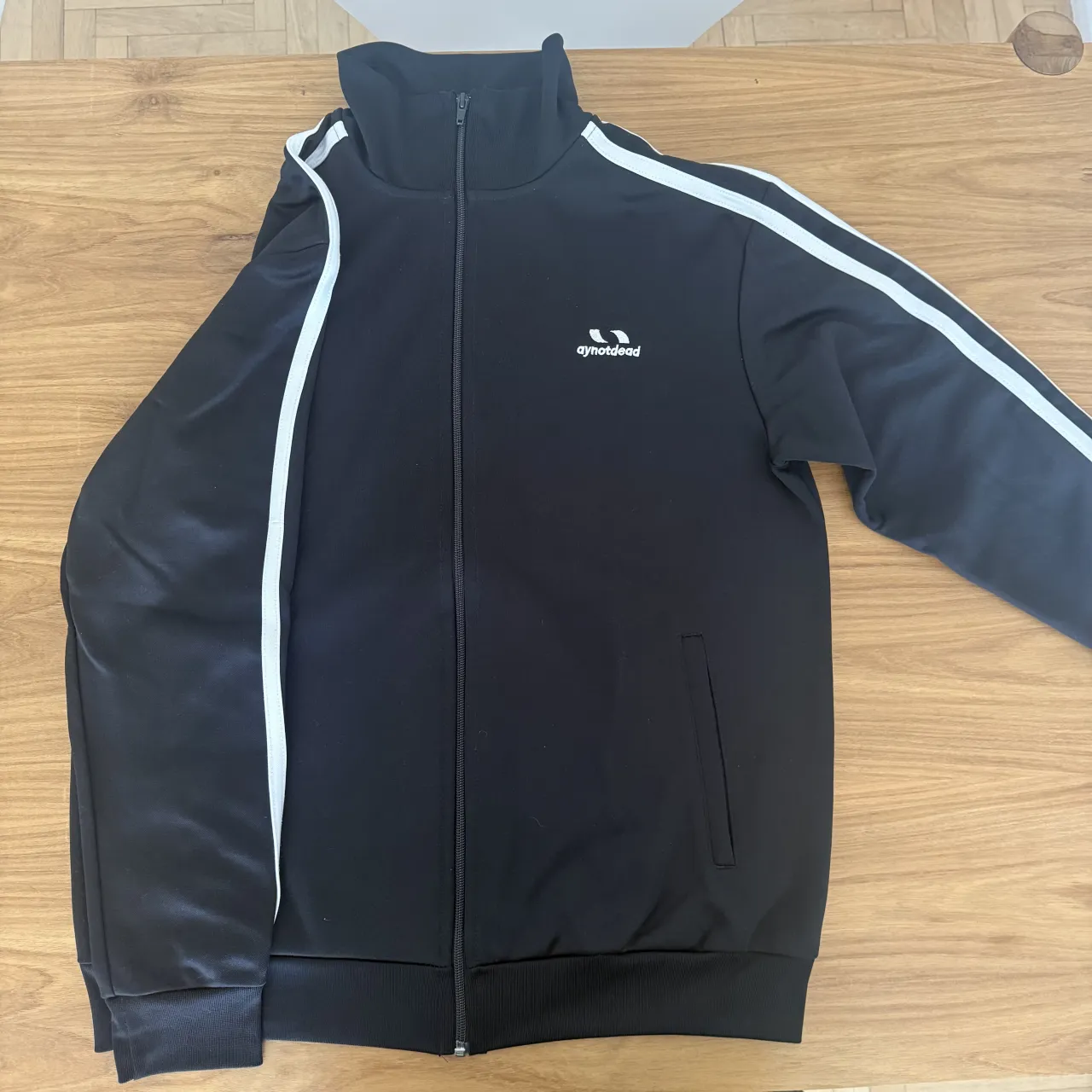 Buzo  de AY NOT DEAD negro con cierre completo y cuello alto. 