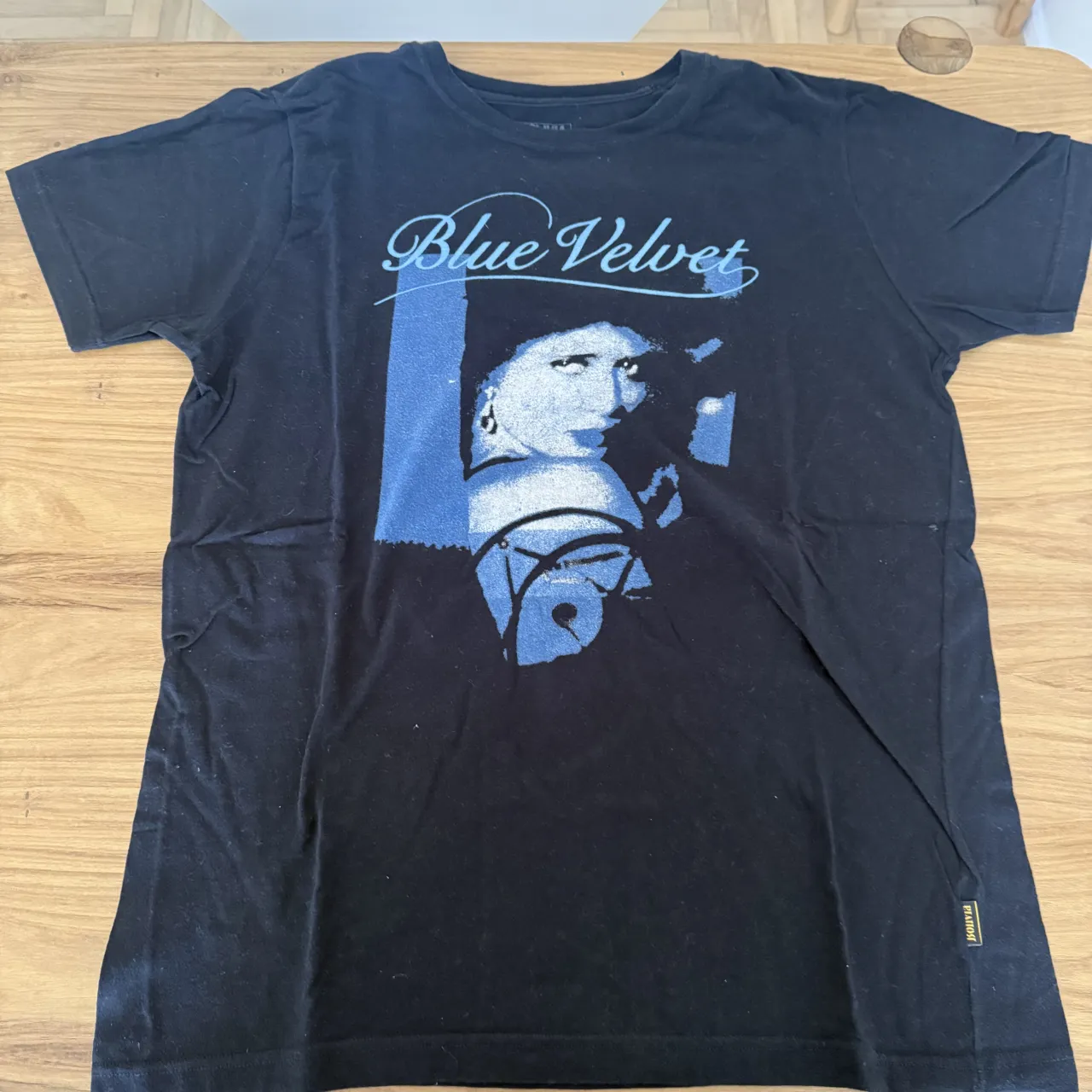 Remera DIVINA BOLIVIA negra con estampa "Blue Velvet" y una imagen en tonos azules de una mujer.