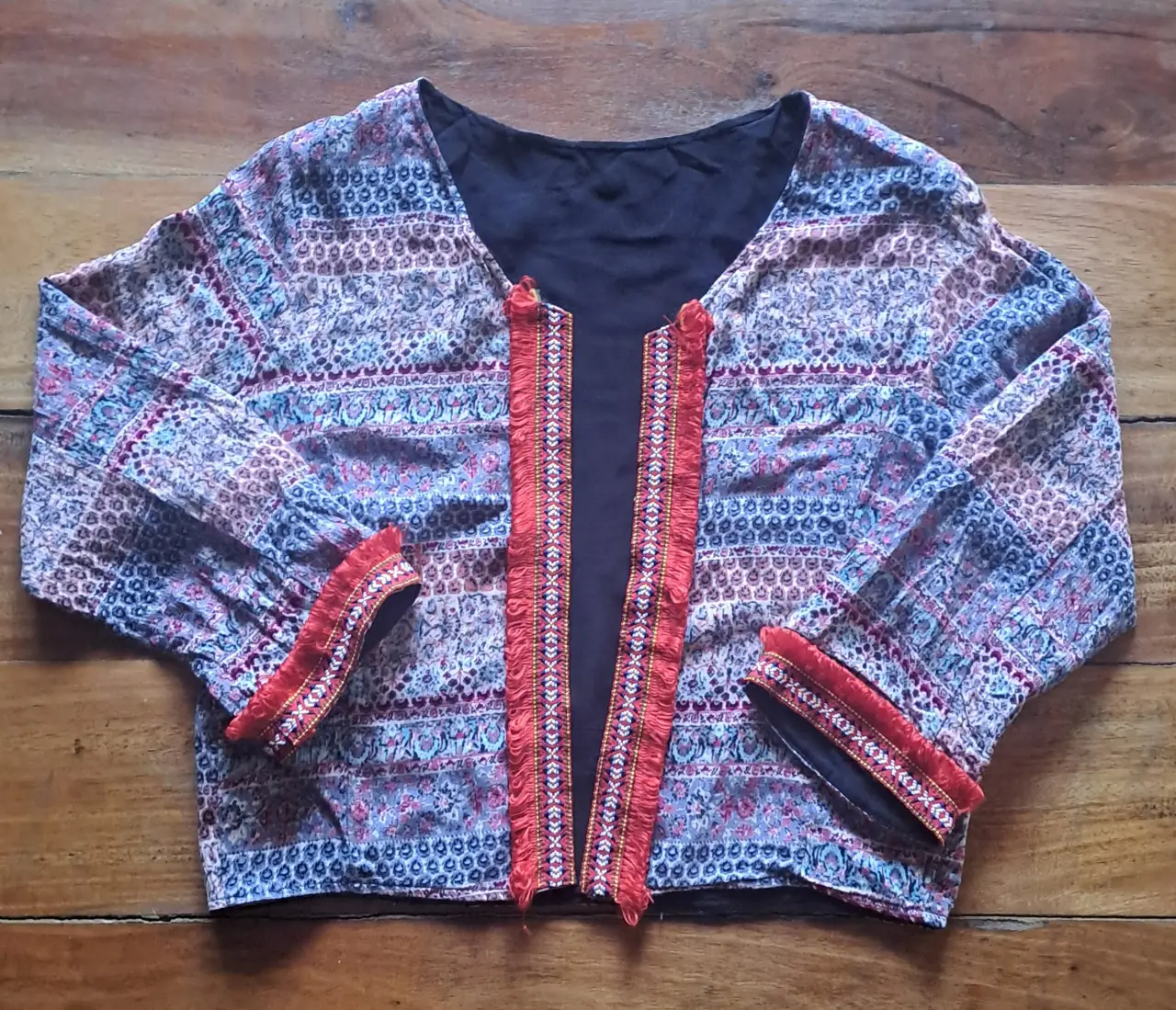 Chaqueta indu estilo con estampado floral y detalles bordados en rojo. Ideal para un look bohemio y casual.