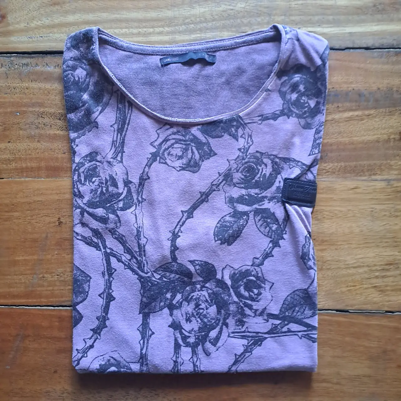 Remera de manga corta para hombre, de color lila con estampado de rosas en negro. 