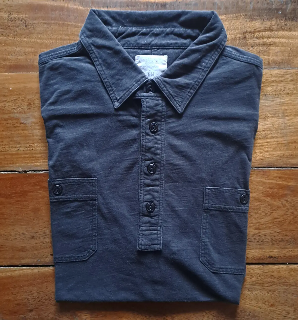 Chomba de hombre de manga corta con cuello tipo polo y bolsillos delanteros Etiqueta Negra. color negro jaspeado. Ideal para un look casual y cómodo.