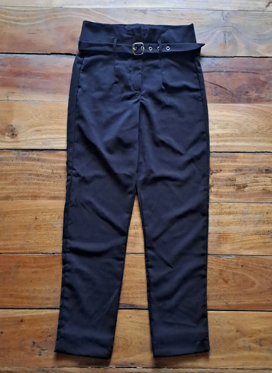 Pantalón sastrero de crepe negro con cinturón y hebilla plateada. Tiro alto y corte recto, ideal para un look formal o de trabajo.