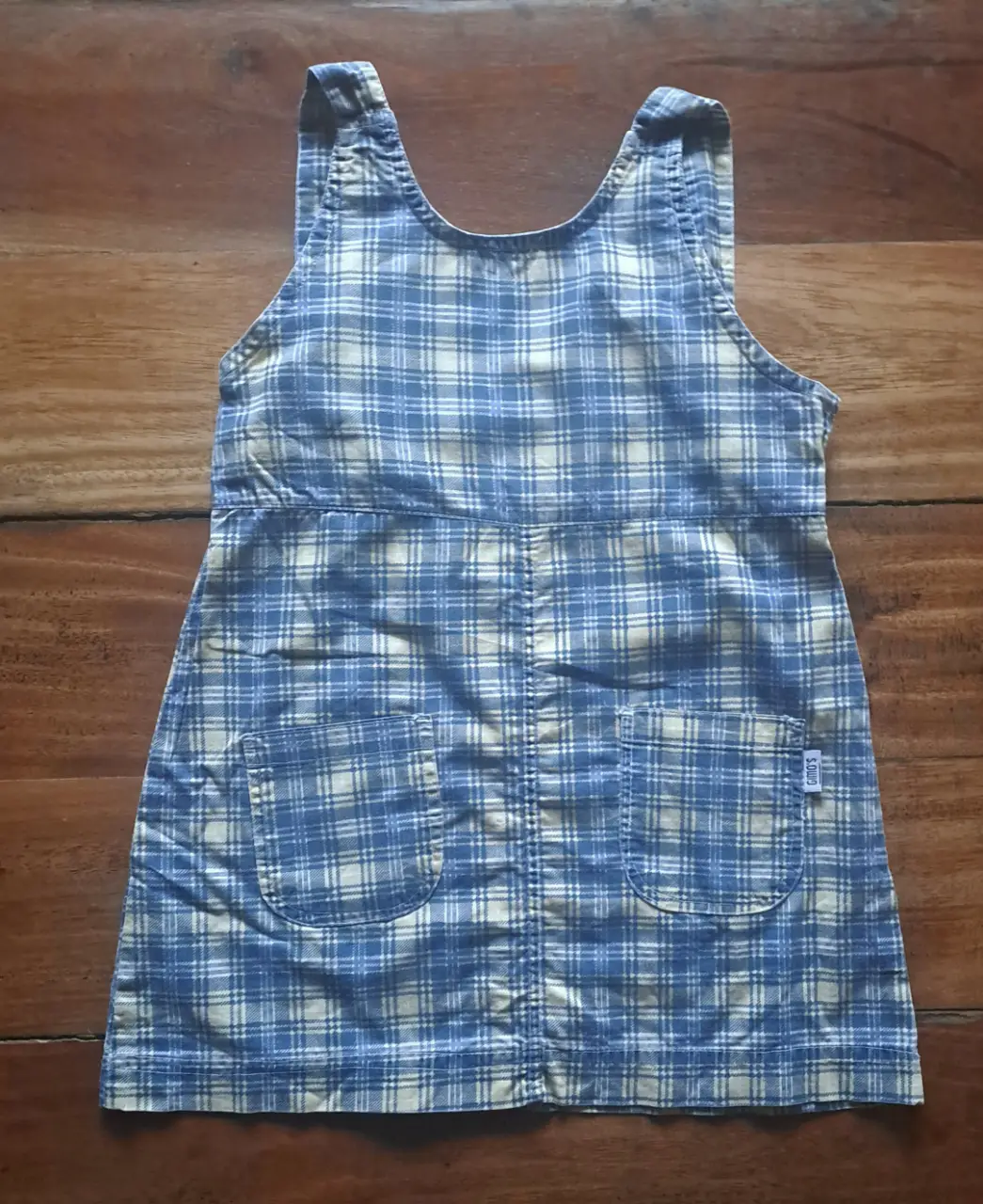 Vestido mini de niña, con estampado a cuadros en tonos azul y amarillo. Posee dos bolsillos delanteros y la marca Gimo's. Ideal para un look casual.
