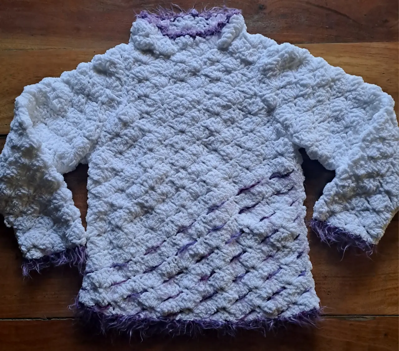 Sweater niña de lana tejido a mano, con medio cuello alto y detalles en color violeta peludito. Ideal para un look abrigado y con estilo.