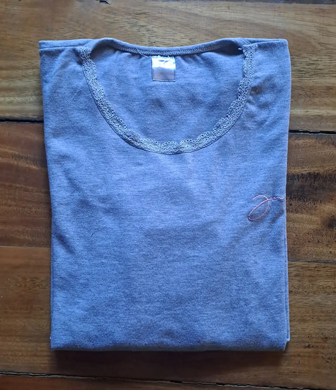Remera camiseta manga larga gris con detalle de encaje en el cuello y bordado en el frente. Ideal para un look casual y cómodo.