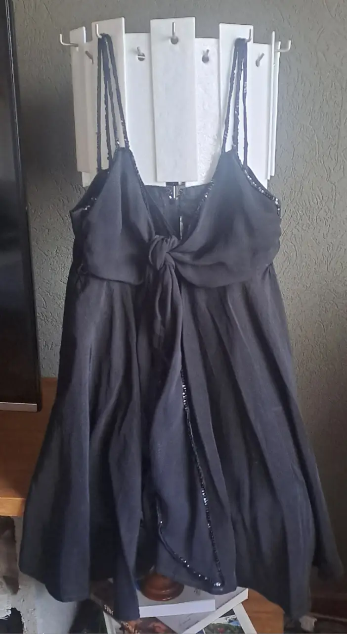 Vestido mini negro con tirantes finos de lentejuelas y detalle de lazo en escote. Ideal para una fiesta o salida nocturna.