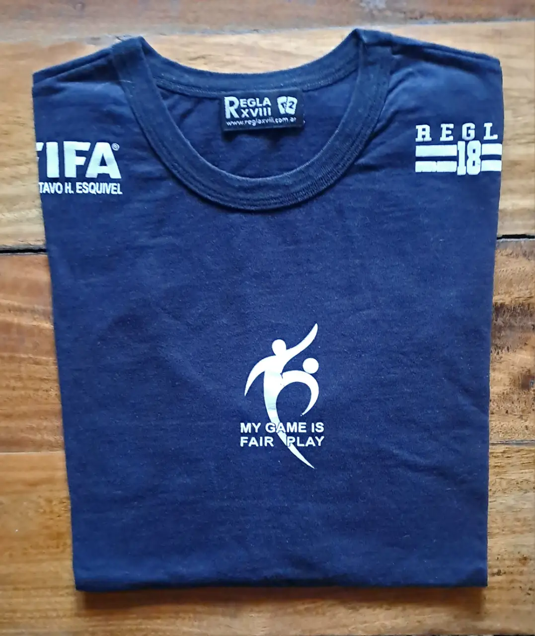 Musculosa deportiva azul oscuro con estampado blanco. Diseño "My game is fair play" y logos de "FIFA" y "Regla XVIII". Ideal para actividades deportivas o uso casual.