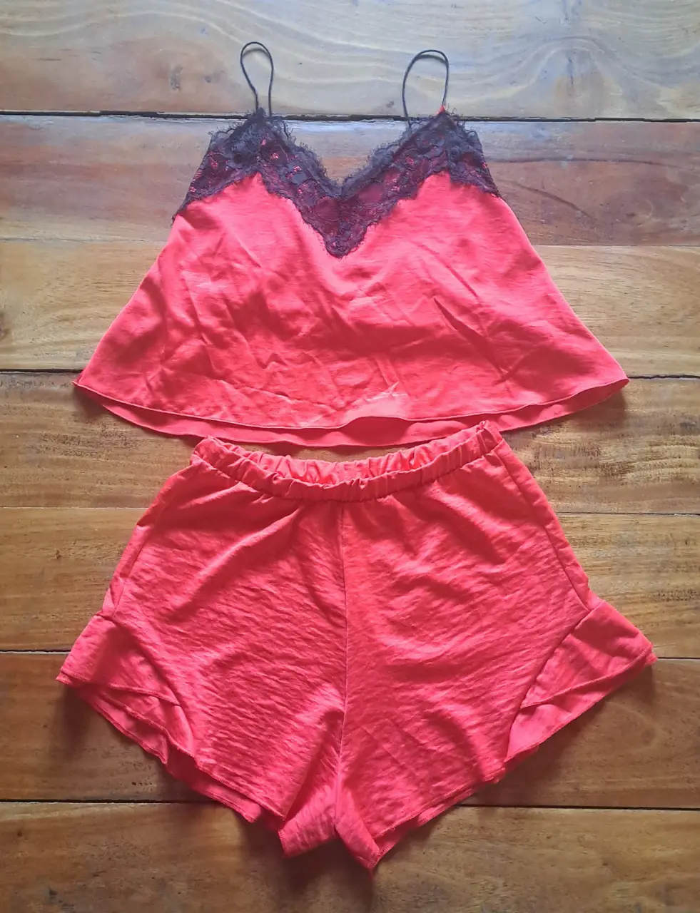 Conjunto de pijama de satén rojo con detalles de encaje negro. Incluye un top con tirantes y shorts a juego, ideal para una noche cómoda 