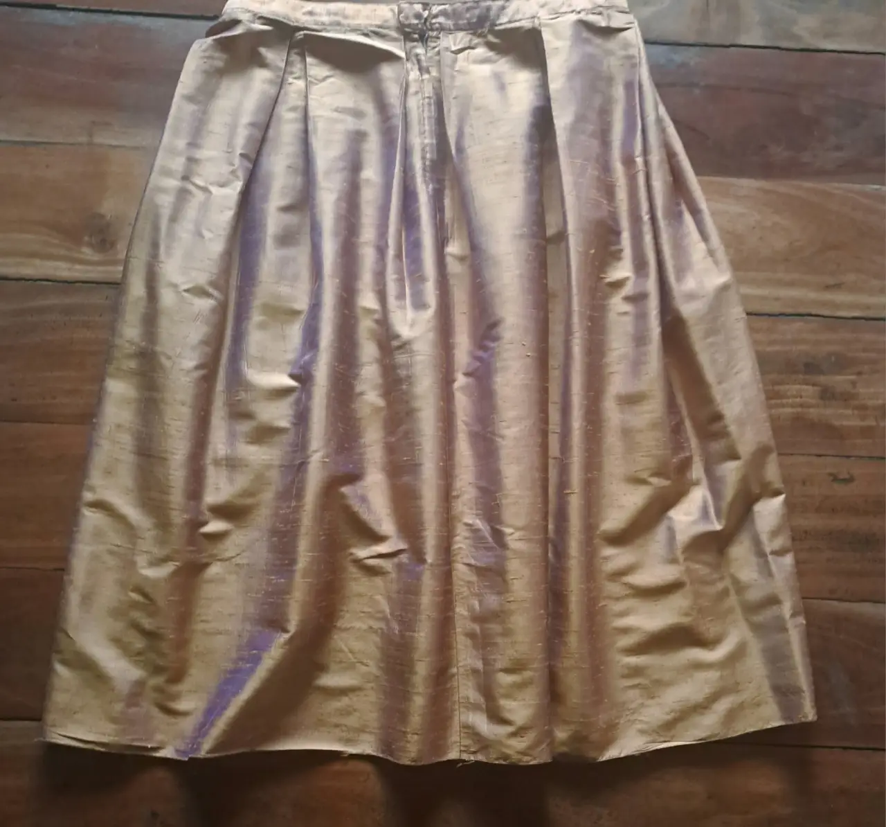 Falda dorada de seda, con pliegues y cierre trasero. Ideal para eventos formales o fiestas.