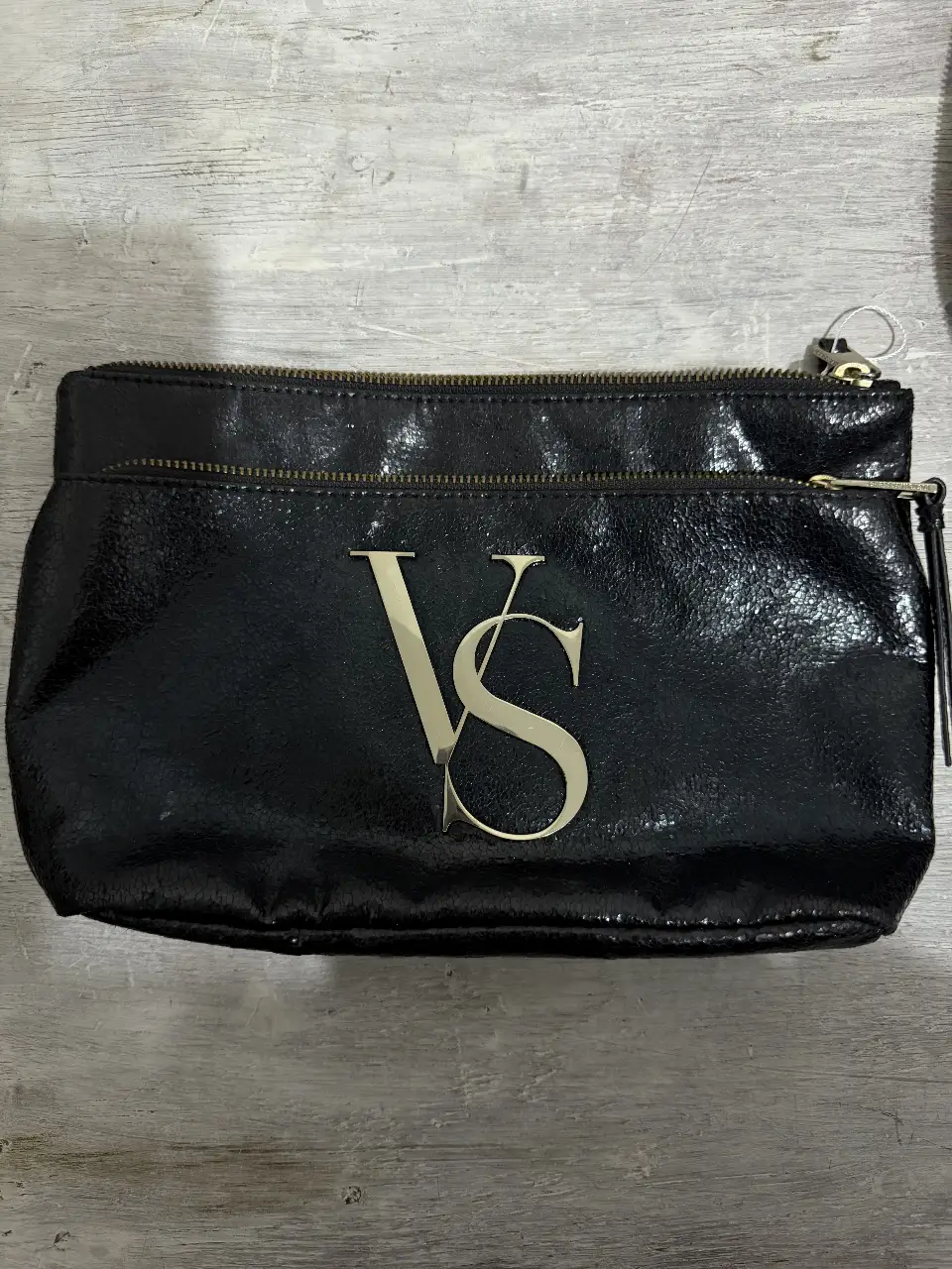 Clutch negro de charol con logo "VS" dorado. Ideal para eventos y salidas.