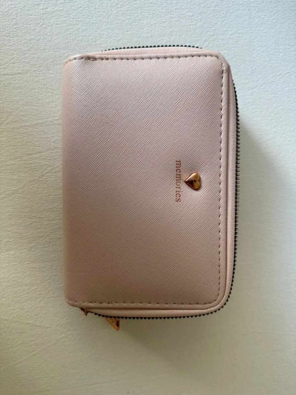 Billetera rosa con cierre y detalle de corazón metálico. Interior con múltiples compartimentos.