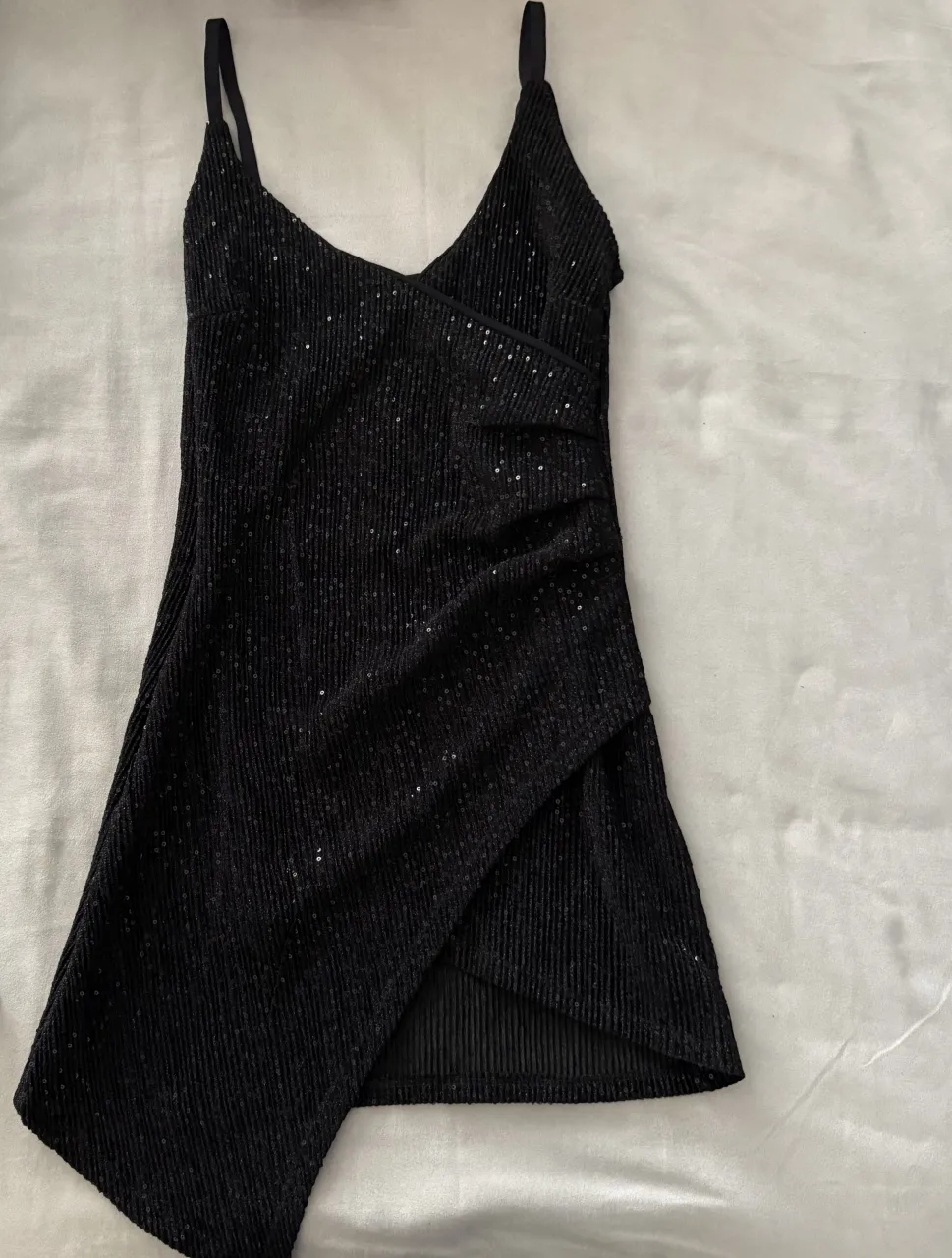 Vestido negro con lentejuelas y detalles fruncidos. Posee breteles finos y escote en V.