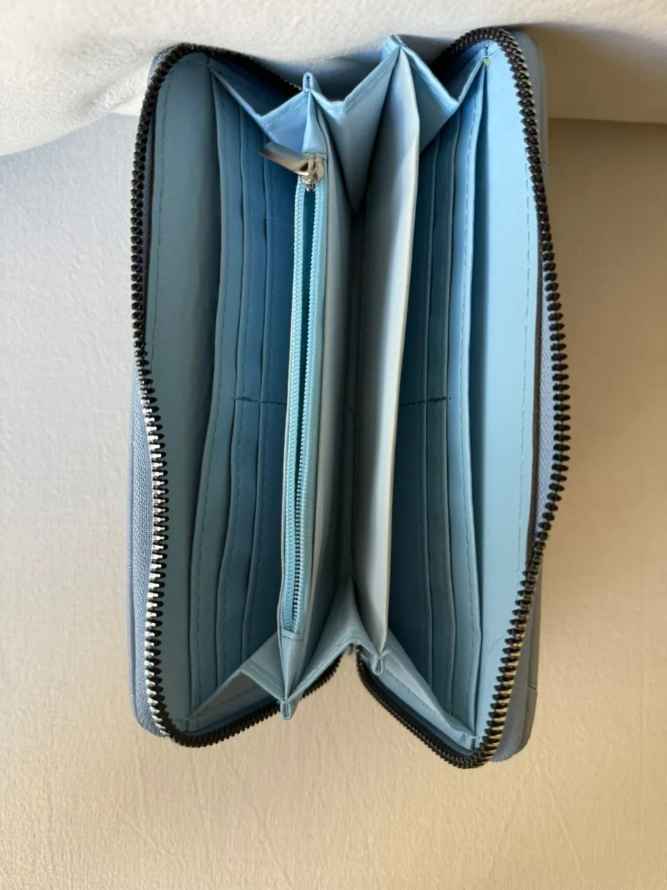 Billetera de cuero sintético con cierre completo y múltiples compartimentos internos. Diseño acolchado con pespuntes en forma de rombos.