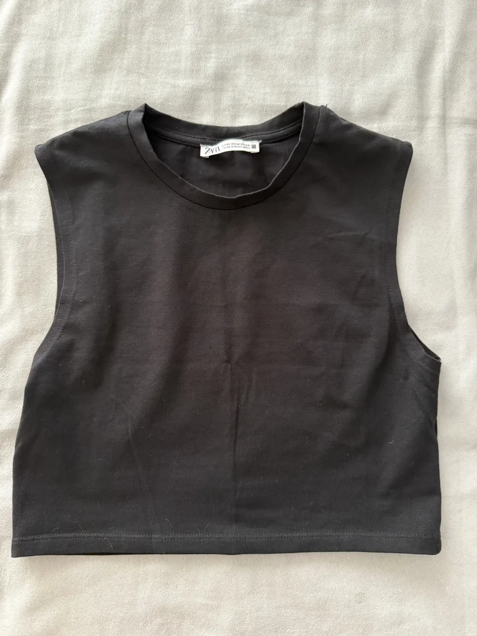 Musculosa negra crop top con hombros marcados. Perfecta para un look casual y moderno.