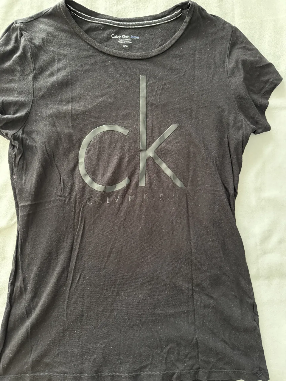 Remera negra de manga corta con logo grande de Calvin Klein Jeans estampado en el frente. Cuello redondo. Ideal para un look casual y moderno.