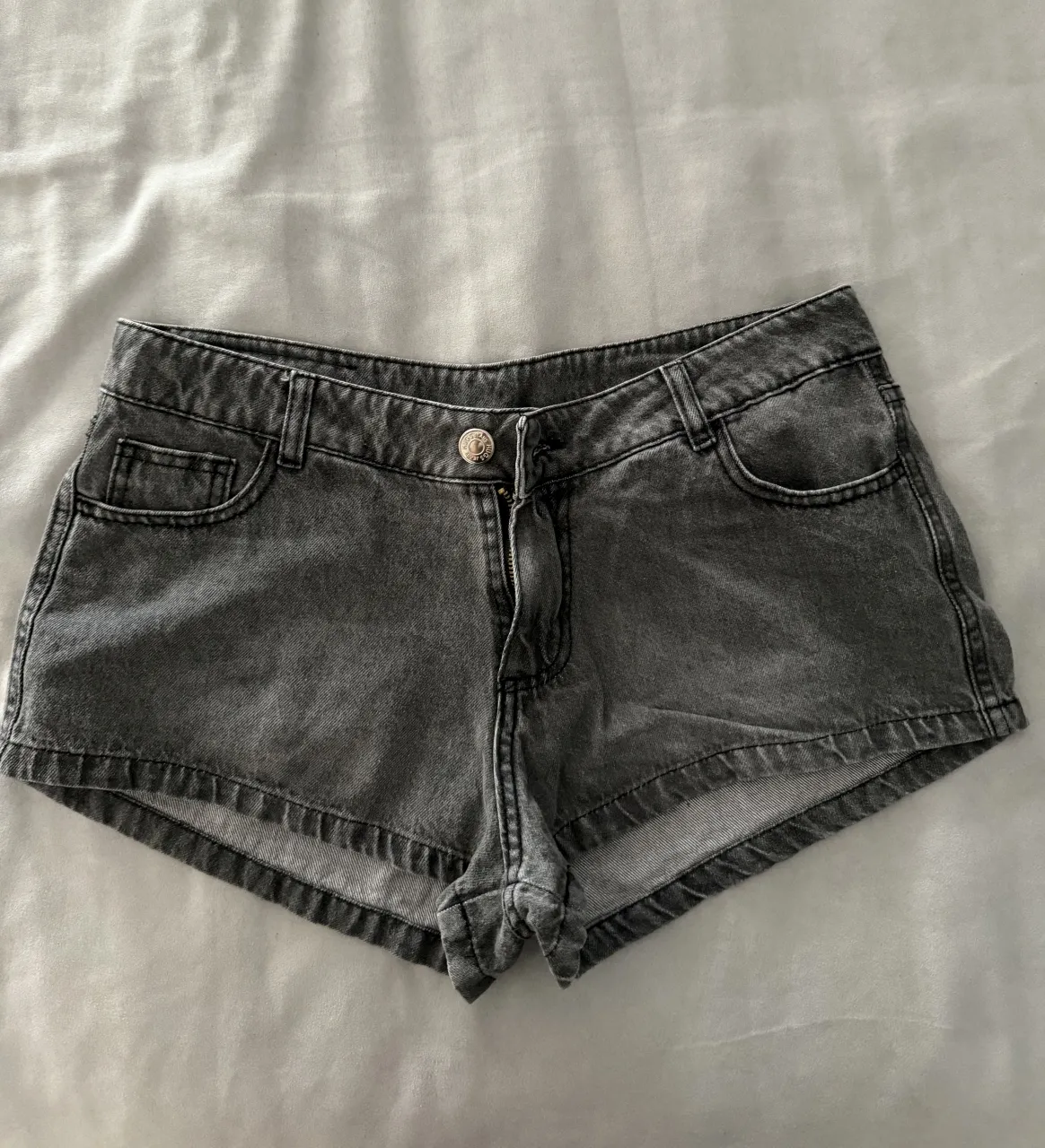 Shorts de jean grises tiro bajo con detalles de costura y bolsillos.