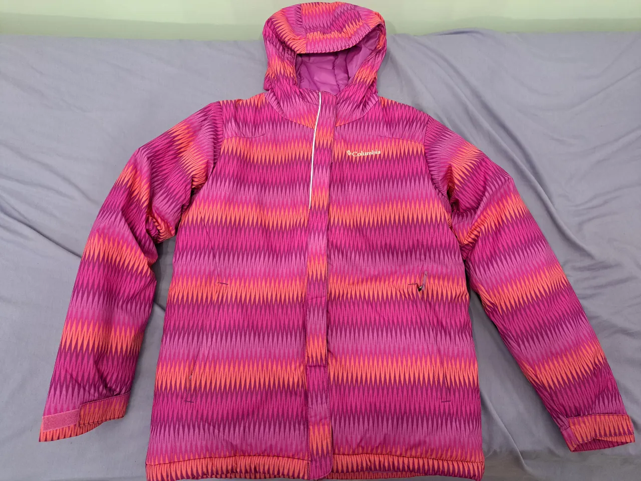 Campera Columbia (nieve/ski) para nena/mujer (talle L, 14-16), con capucha, diseño geométrico en tonos rosa y naranja. Ideal para actividades al aire libre y deportes de invierno. Cuenta con cierre y bolsillos.