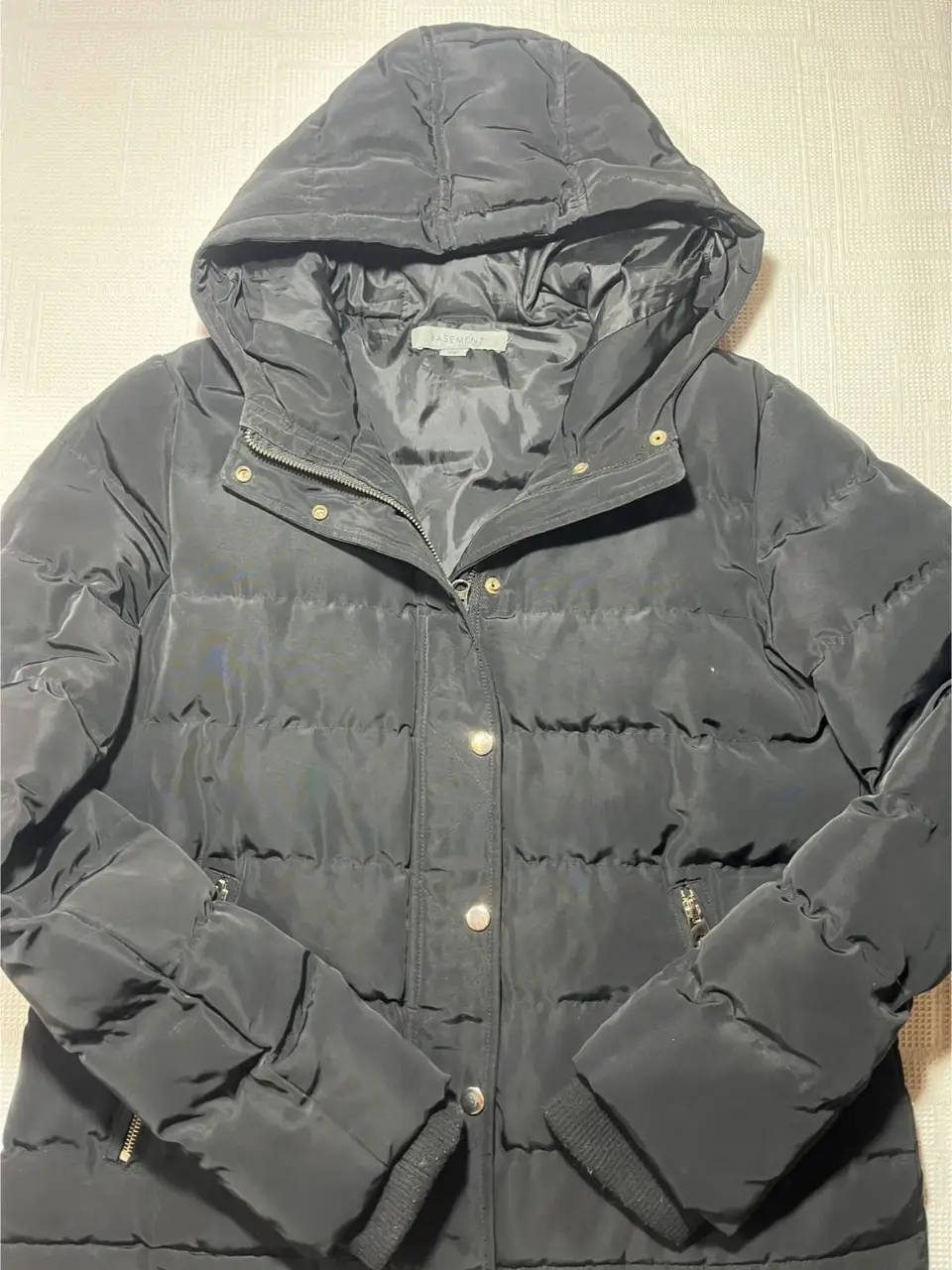 Campera de pluma negra con capucha, ideal para el invierno. Cuenta con cierre y botones, bolsillos con cierre y puños tejidos. Perfecta para mantenerte abrigada y cómoda en cualquier ocasión.