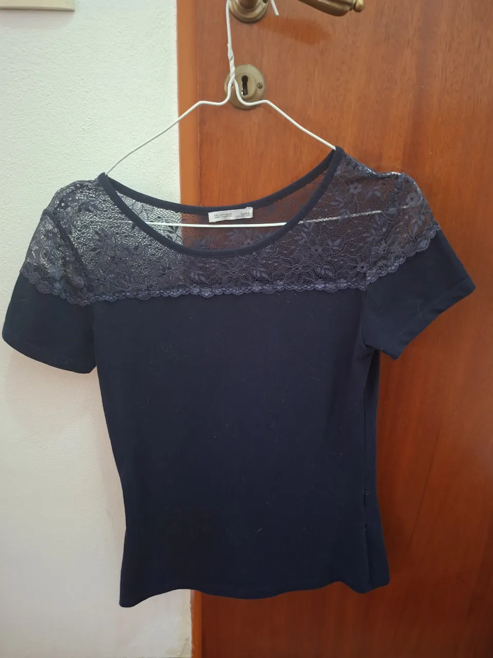 Remera azul marino con detalles de encaje en el cuello y mangas cortas. Ideal para un look casual o para salir.