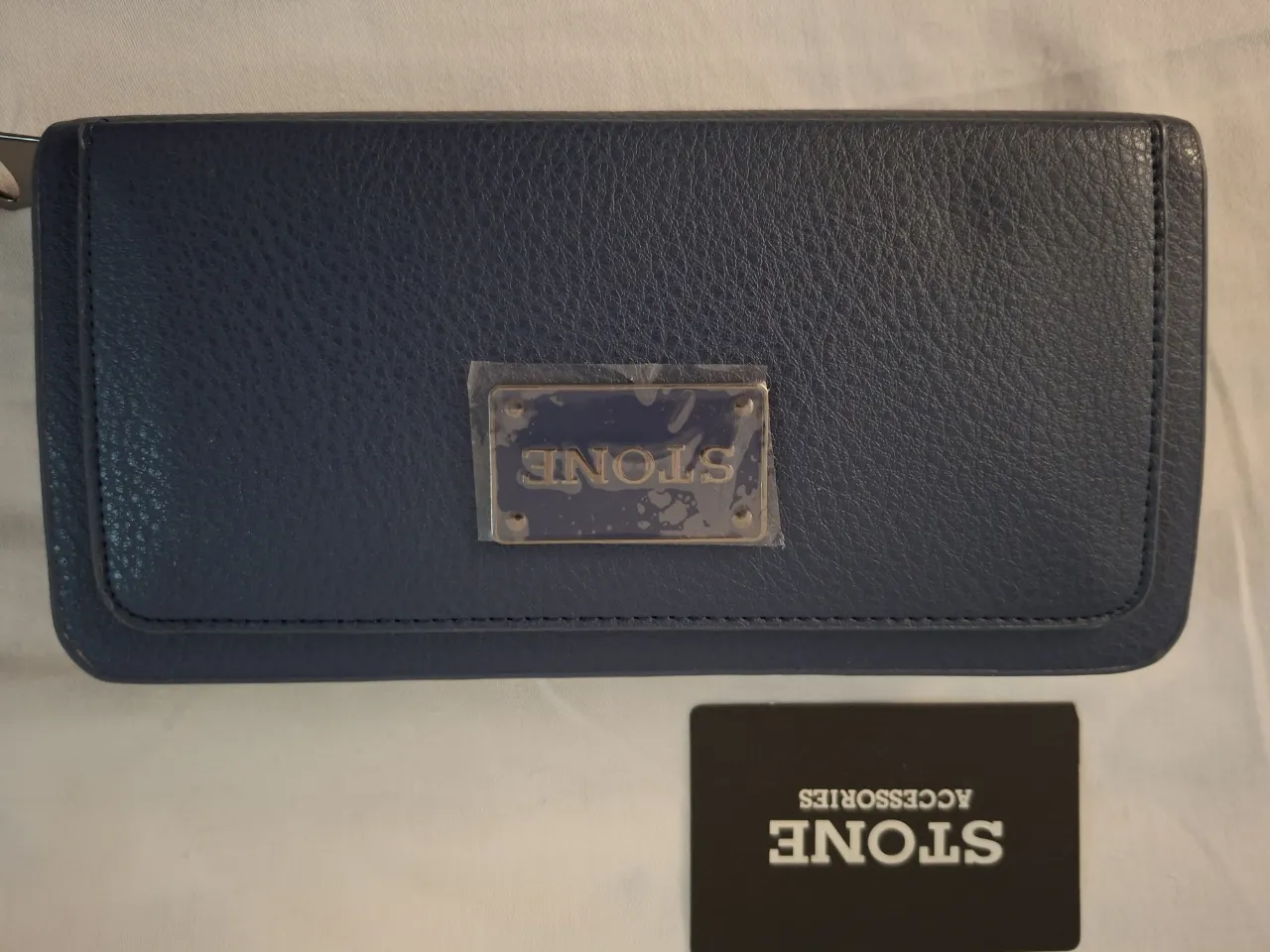 Billetera azul de cuero sintético, con placa metálica dorada y logo de la marca. Interior forrado a rayas, con múltiples compartimentos y cierre.