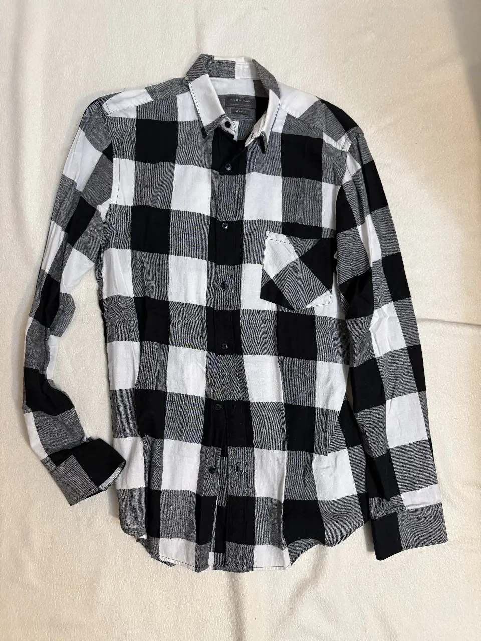 Camisa a cuadros en blanco y negro para hombre, de manga larga, ideal para un look casual y moderno. Confeccionada en tela de algodón suave y cómoda, perfecta para usar en cualquier ocasión.