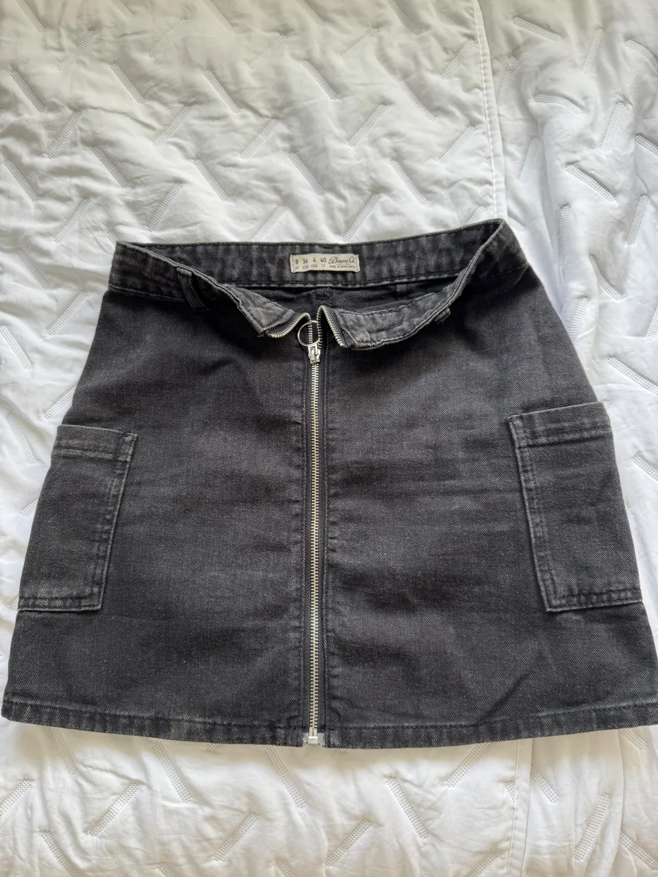 Pollera de jean negra, tiro alto, con bolsillos cargo y cierre metálico al frente. Un básico canchero para armar looks modernos.