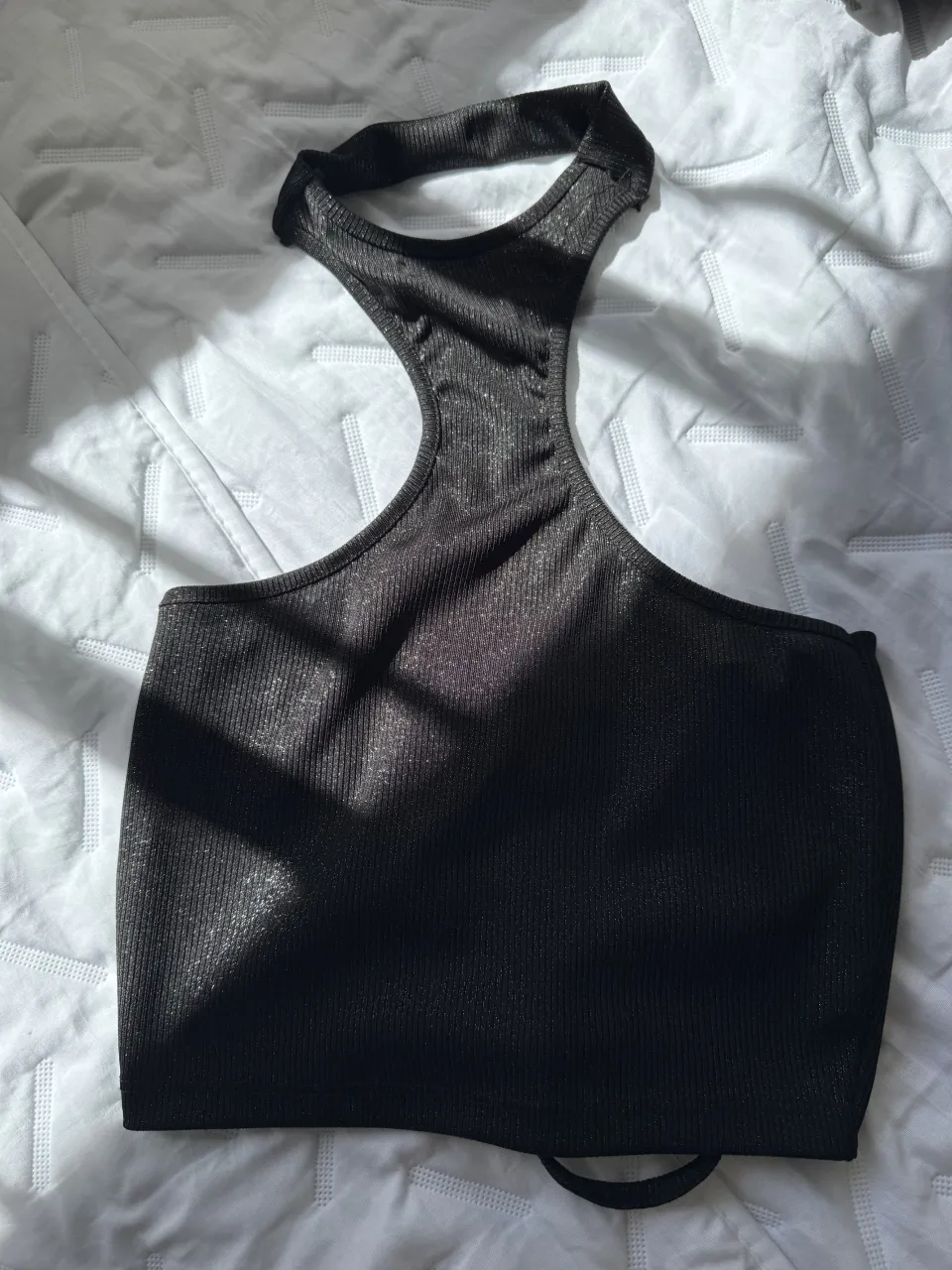 Top negro con fruncido y cordón ajustable en la parte delantera. Posee un diseño con un solo hombro y tiras finas en la espalda.