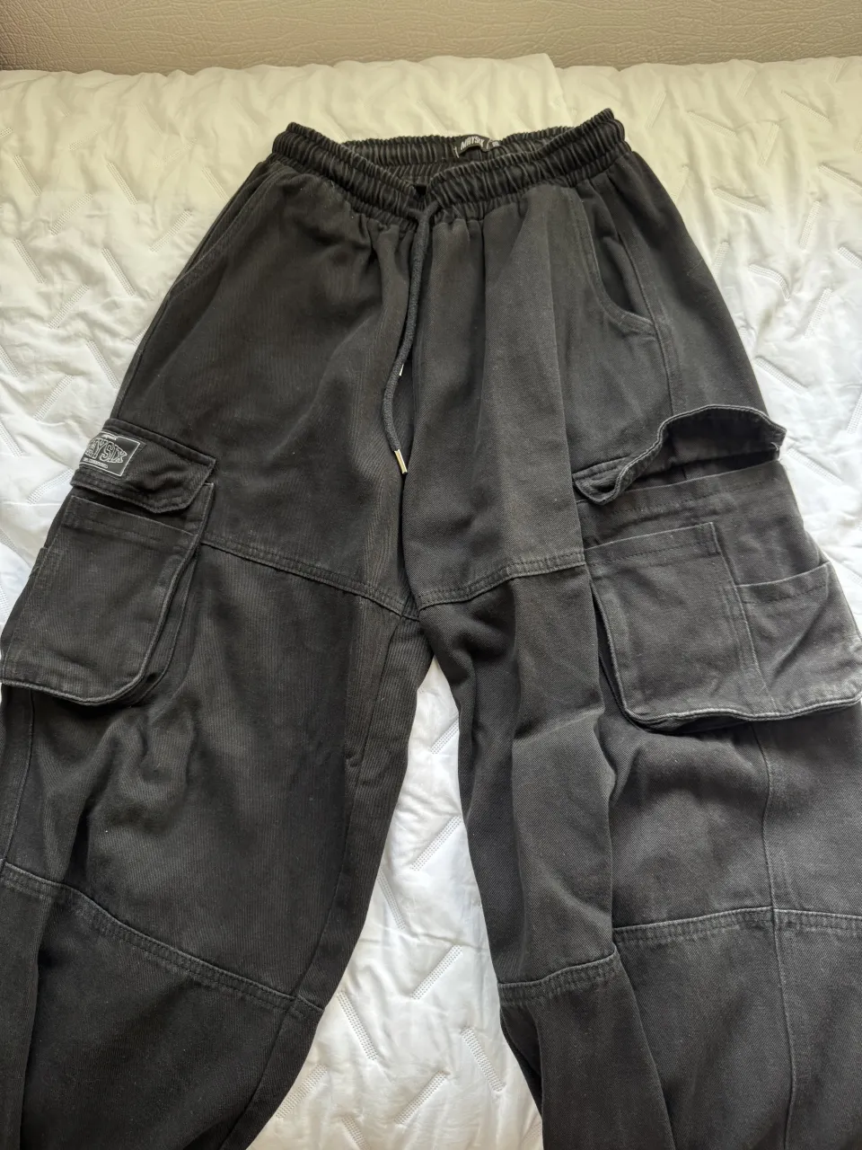 Pantalón cargo negro, tiro alto, con cordón ajustable en la cintura y puños. Diseño moderno y cómodo, ideal para un look urbano y canchero.