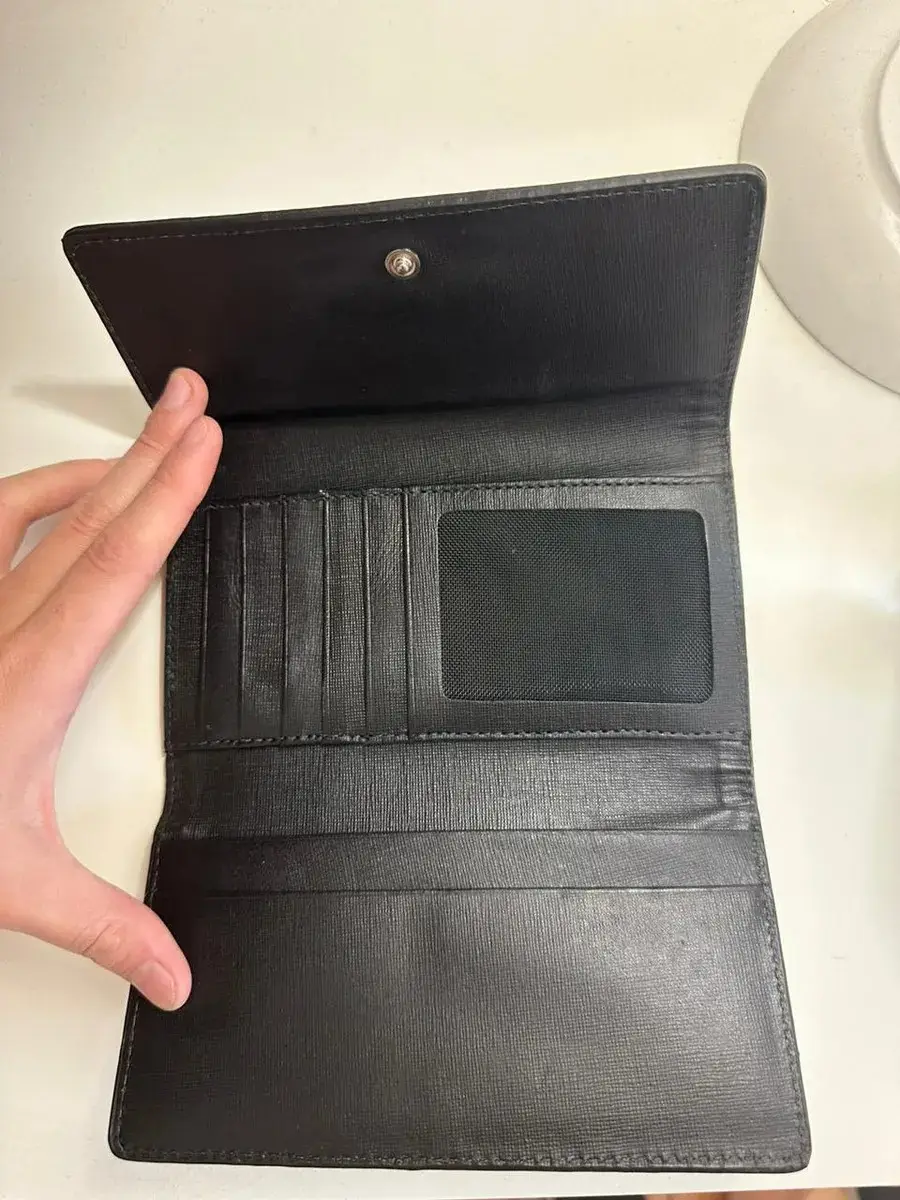 Billetera de cuero negro, con cierre y compartimentos internos. Ideal para organizar tus pertenencias con estilo y practicidad. Cuenta con el logo de la marca "CARTERAS ITALIANAS CASA FONDATA NEL 1963".