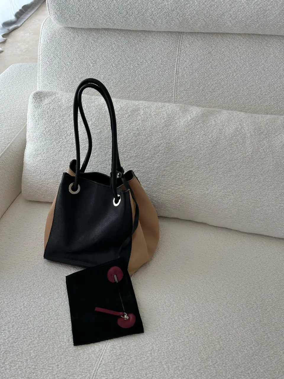 Cartera tipo tote bag de cuero, con detalles en dos colores. Incluye un sobre a juego con cierre.