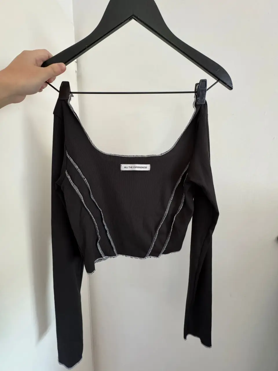 Top negro de manga larga con detalles de costura en blanco. Corte ajustado y escote cuadrado. Ideal para un look moderno y versátil.