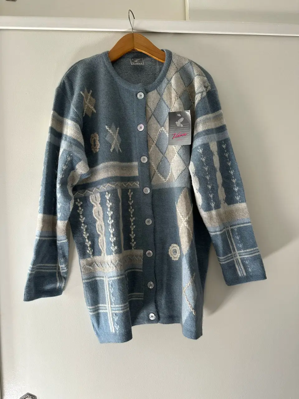 Cardigan de lana tejido con diseño geométrico en tonos celeste y beige. Cierre con botones.